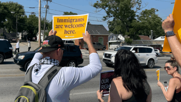 An Omahan holds a sign reading "Immigrants are welcome here" at a spontaneous protest following an ICE raid in Omaha.