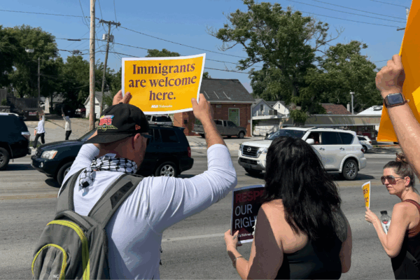 An Omahan holds a sign reading "Immigrants are welcome here" at a spontaneous protest following an ICE raid in Omaha.