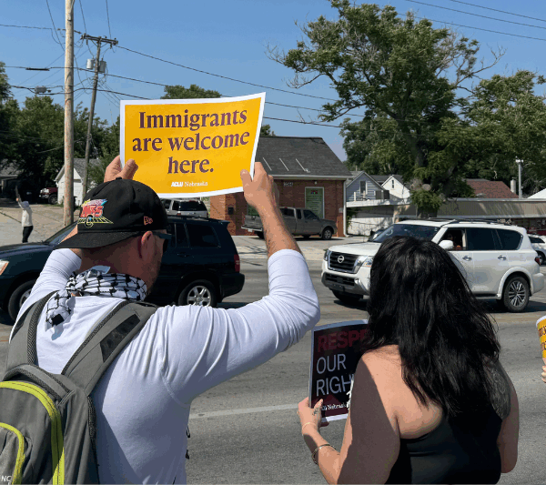 An Omahan holds a sign reading "Immigrants are welcome here" at a spontaneous protest following an ICE raid in Omaha.