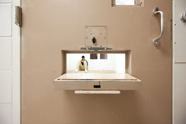 Peering through a food tray hole to see a youth in a solitary cell. © Richard Ross www.juvenile-in-justice.com