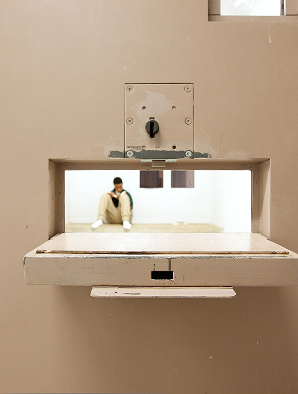 Peering through a food tray hole to see a youth in a solitary cell. © Richard Ross www.juvenile-in-justice.com