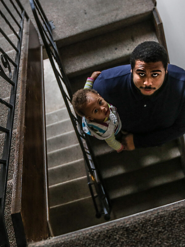 Jacob holding his daughter in the stairwell of their apartment building.