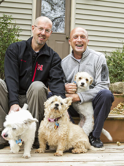 Todd and Joel outside of their home with their dogs.