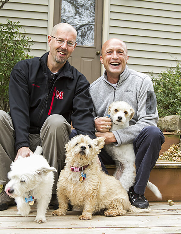 Todd and Joel outside of their home with their dogs.