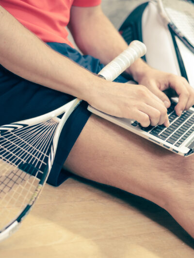 student with laptop and tennis racket