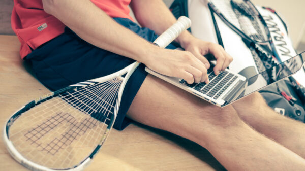 student with laptop and tennis racket