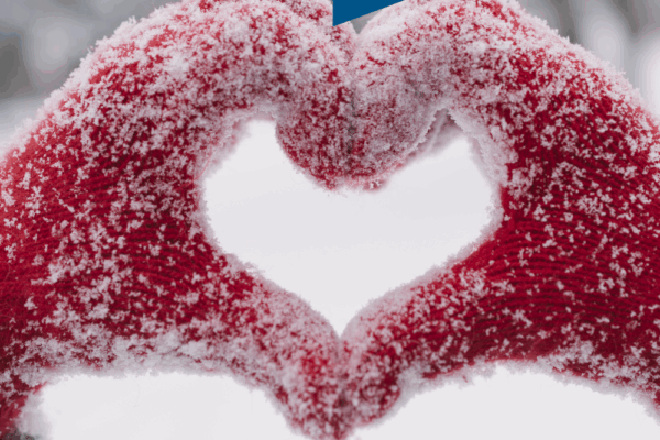 Photo of red gloovers, govered with snow, forming a heart