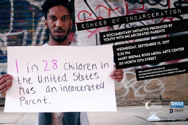 Photo of Man Holding Sign saying "1 in 28 children in the US has an incarcerated parent."