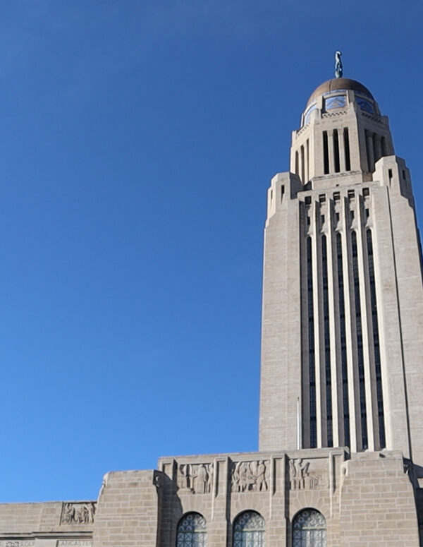 The Nebraska State Capitol stands against a blue sky.