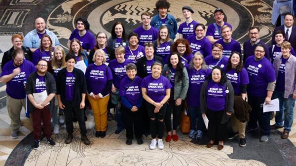 Photo taken from above and angled down. Nebrakans wearing purple shirts pose in the Nebraska Capitol Rotunda