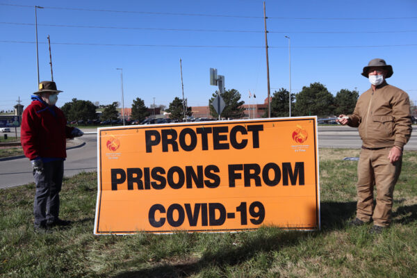 Rex Walton and Paul Feilmann hold a sign reading "Protect prisons from COVID-19" outside of the Nebraska State Penitentiary.