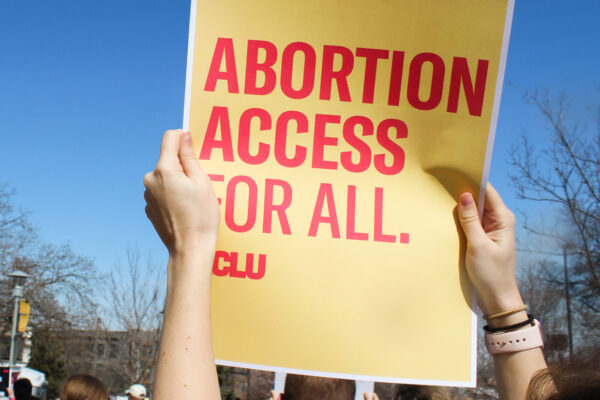 A protester holds a sign reading "Abortion access for all."