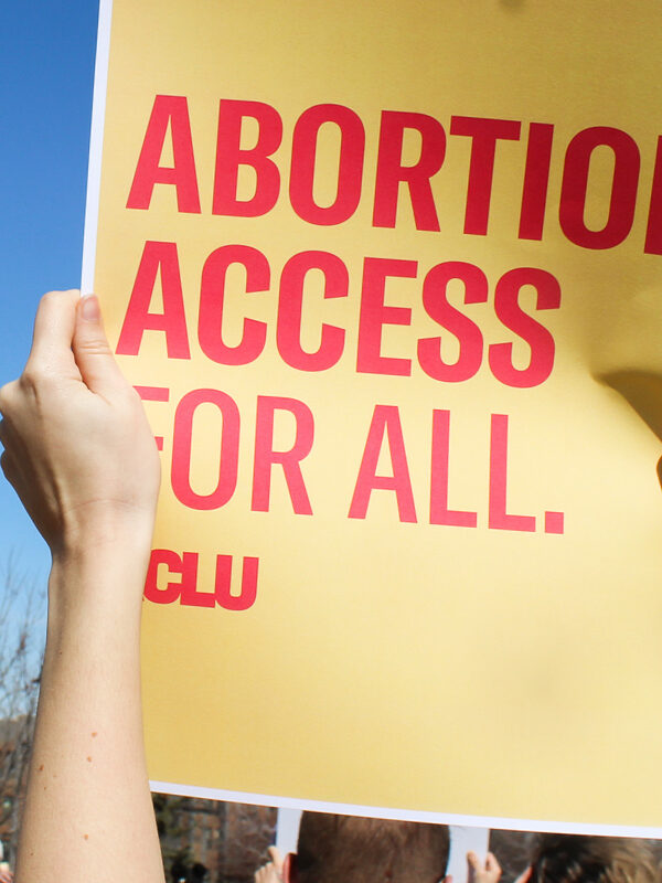 A protester holds a sign reading "Abortion access for all."