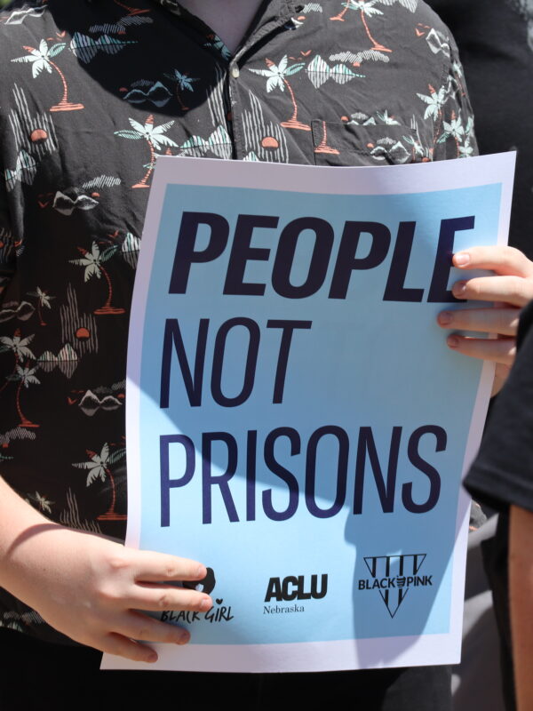 A protester holds a sign reading "People not prisons."