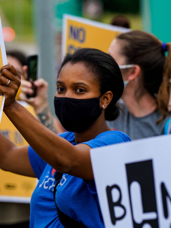 A protester holds a sign reading "No Cops in Schools."