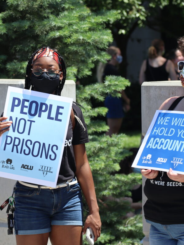 Protesters hold signs reading "People not Prisons" and "We Will Hold You Accountable"