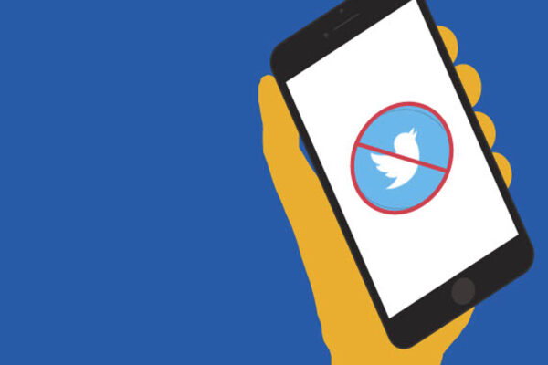 A graphic depicting a hand holding a phone with a red "X" over the Twitter icon.