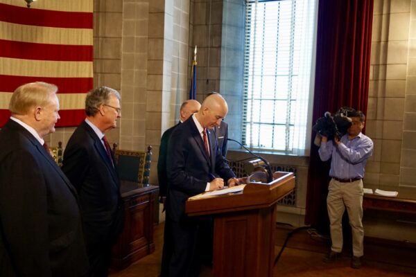 A photojournalist (right) films Gov. Ricketts at a signing event.