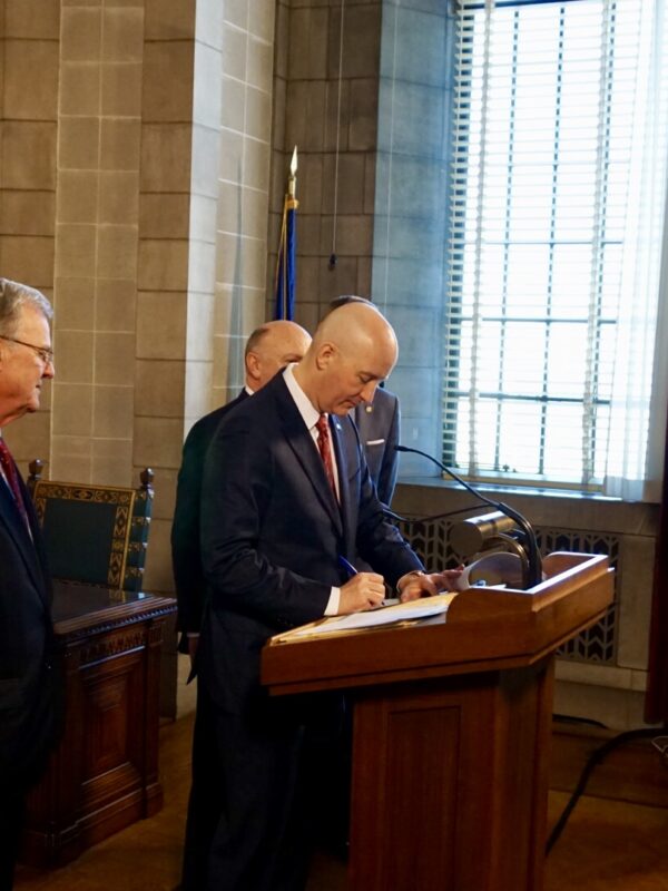 A photojournalist (right) films Gov. Ricketts at a signing event.