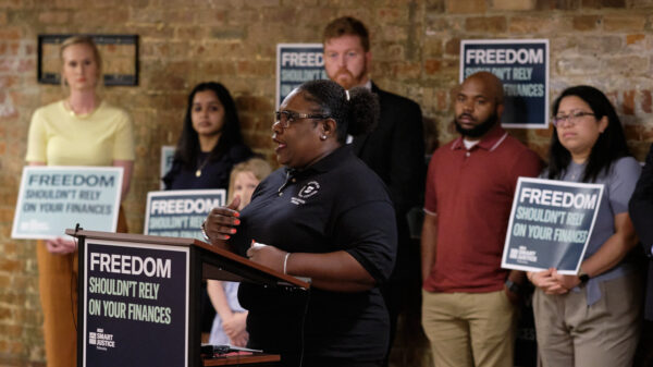 Program volunteer Demetrius Gatson speaks at a podium that reads "Freedom shouldn't rely on your finances."