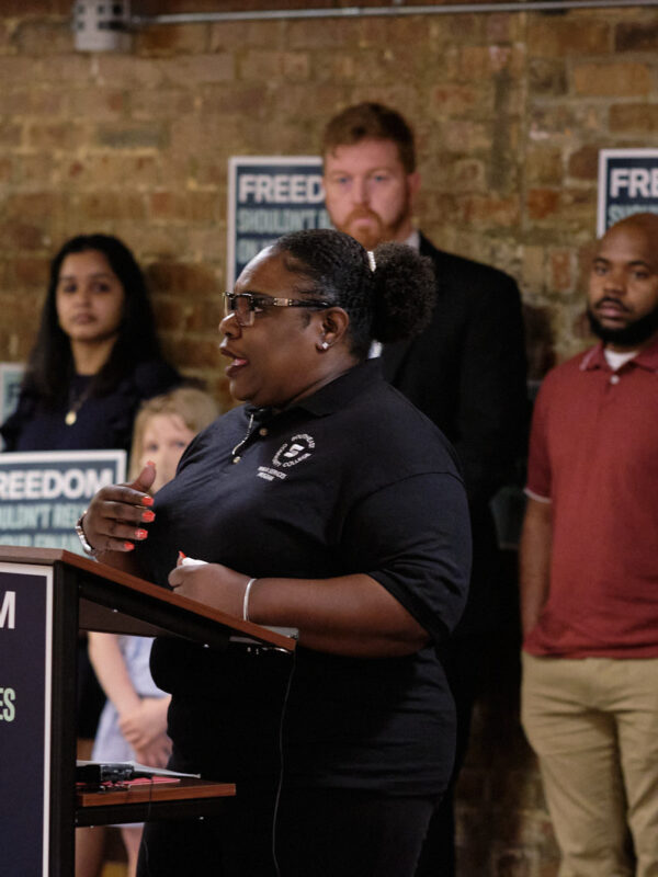 Program volunteer Demetrius Gatson speaks at a podium that reads "Freedom shouldn't rely on your finances."