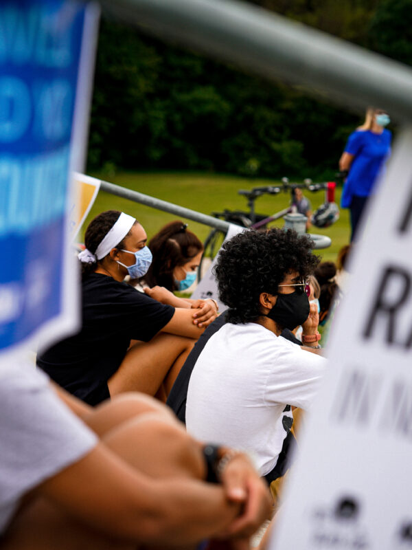 Students sit listening to a speaker at an Educators for Black Lives rally. A sign nearby reads Fight Racism in Nebraska.