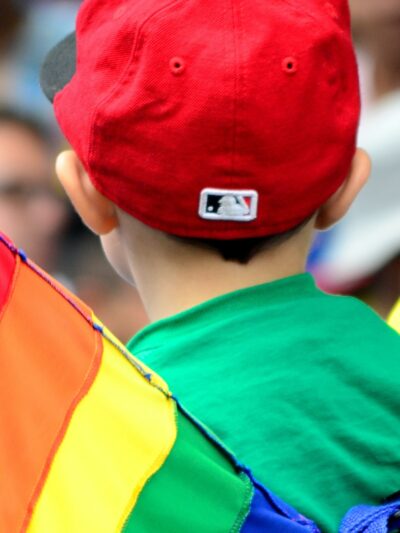 A child stands near a Pride flag.