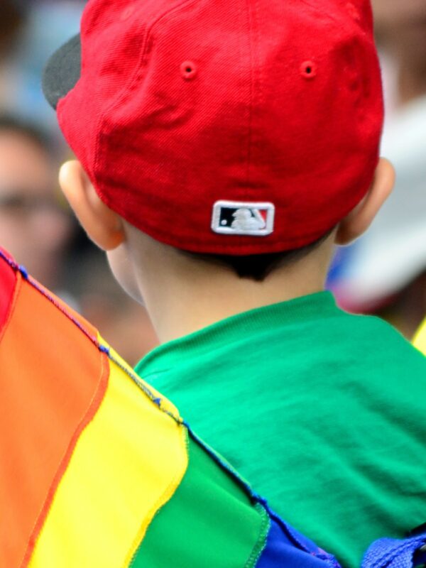 A child stands near a Pride flag.