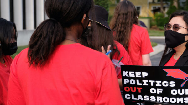 Students speak together at a rally before the University of Nebraska Board of Regents meeting. One holds a sign reading "Keep politics out of our classrooms."