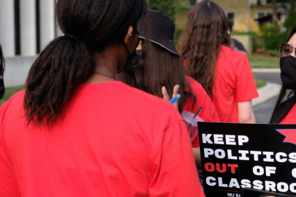 Students speak together at a rally before the University of Nebraska Board of Regents meeting. One holds a sign reading "Keep politics out of our classrooms."