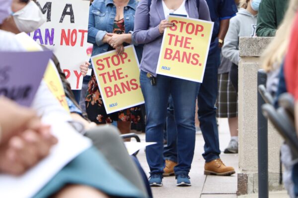 Attendees hold signs at an Omaha reproductive rights rally, reading "Stop. The. Bans."