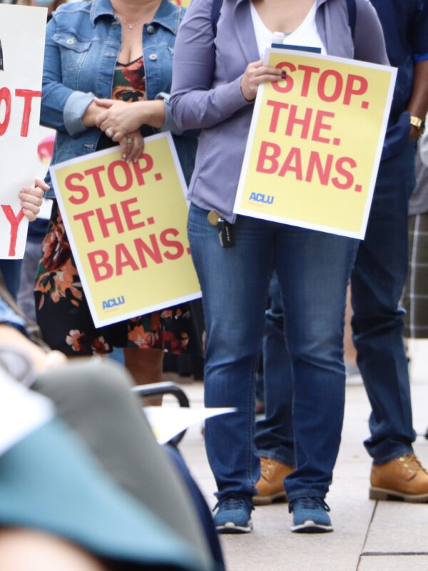 Attendees hold signs at an Omaha reproductive rights rally, reading "Stop. The. Bans."