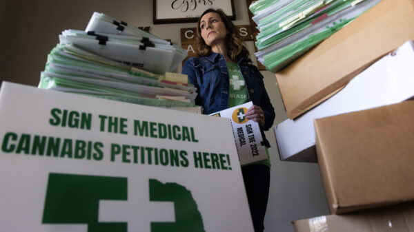 Plaintiff Crista Eggers stands next to collected signatures at her home.