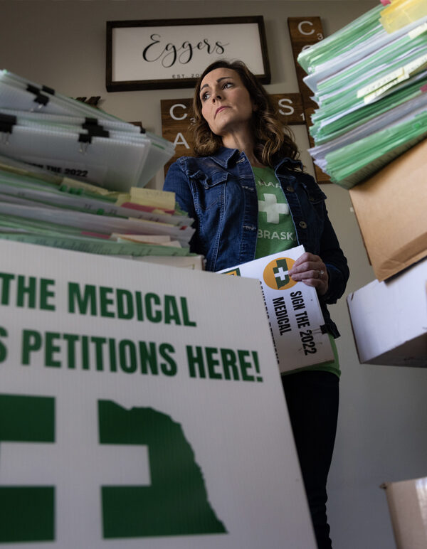 Plaintiff Crista Eggers stands next to collected signatures at her home.