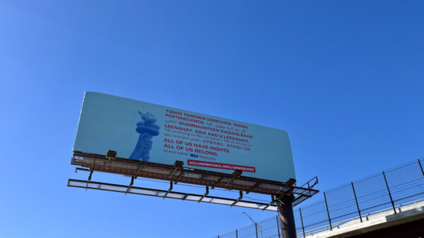 A light blue billboard shows the Statue of Liberty's torch next to translated text, all reading "All of us have rights. All of us belong."