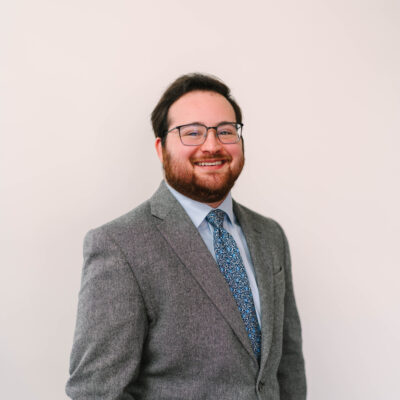Grant Friedman, is a white man with short brown hair and a beard, wearing glasses.