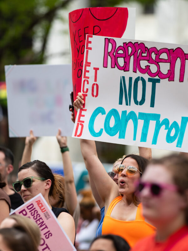 A Nebraskan holds a sign reading "Elected to Represent. Not Control."