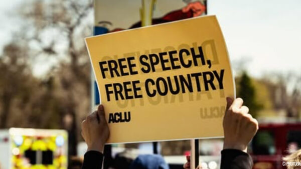 A rally attendee in Omaha holds an ACLU sign reading "FREE SPEECH, FREE COUNTRY."