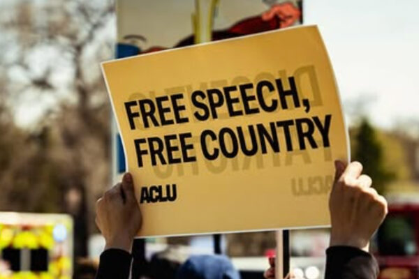 A rally attendee in Omaha holds an ACLU sign reading "FREE SPEECH, FREE COUNTRY."