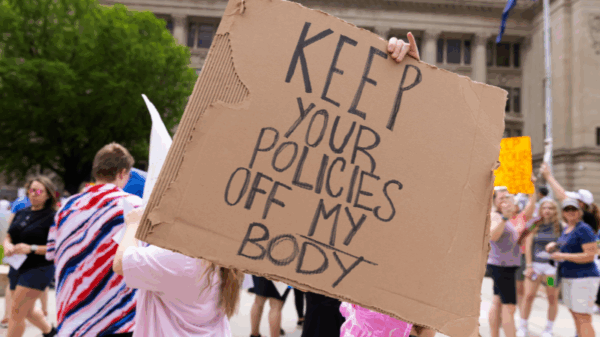 A rally attendee holds a sign at an abortion rights protest in Omaha reading "Keep your policies off my body."