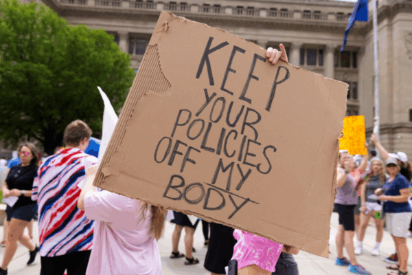 A rally attendee holds a sign at an abortion rights protest in Omaha reading "Keep your policies off my body."