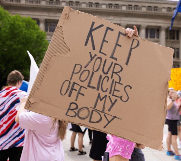 A rally attendee holds a sign at an abortion rights protest in Omaha reading "Keep your policies off my body."