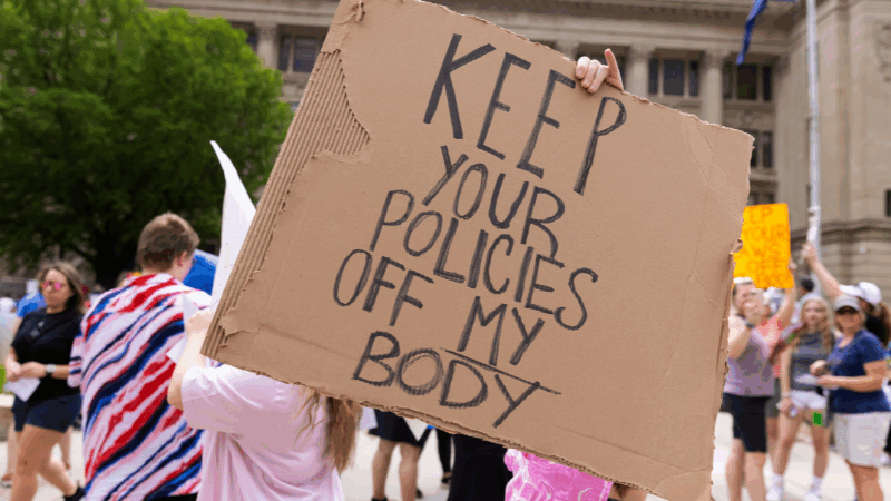 A rally attendee holds a sign at an abortion rights protest in Omaha reading "Keep your policies off my body."