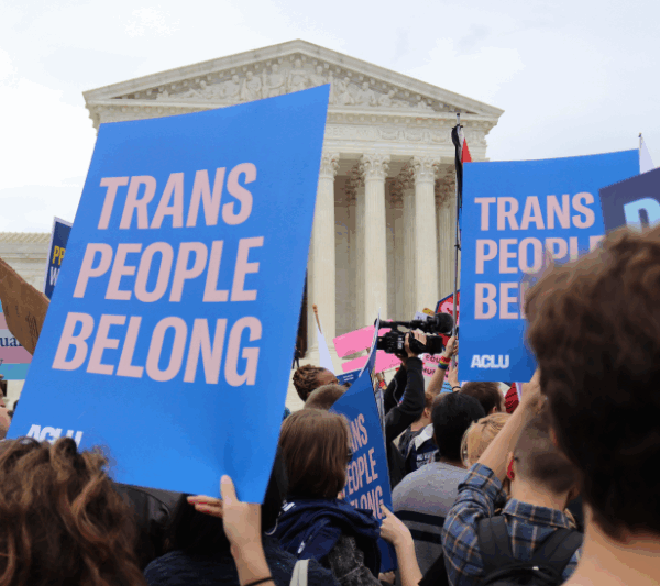 Rally attendees outside the US Supreme Court hold signs reading "Trans people belong"