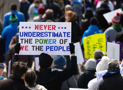 An Omaha rally attendee holds a sign reading "never underestimate the power of we the people."