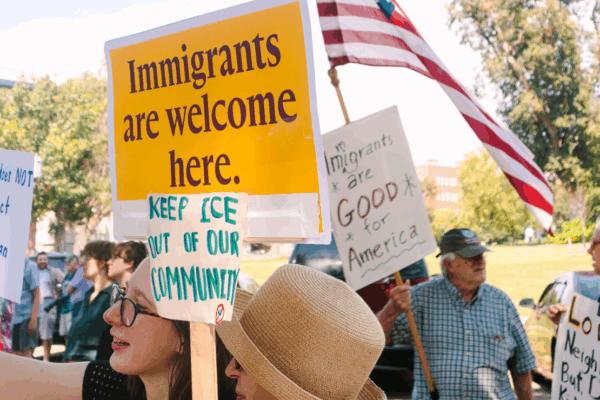 Rally attendees hold signs in support of immigrants at a demonstration outside the governor's mansion.