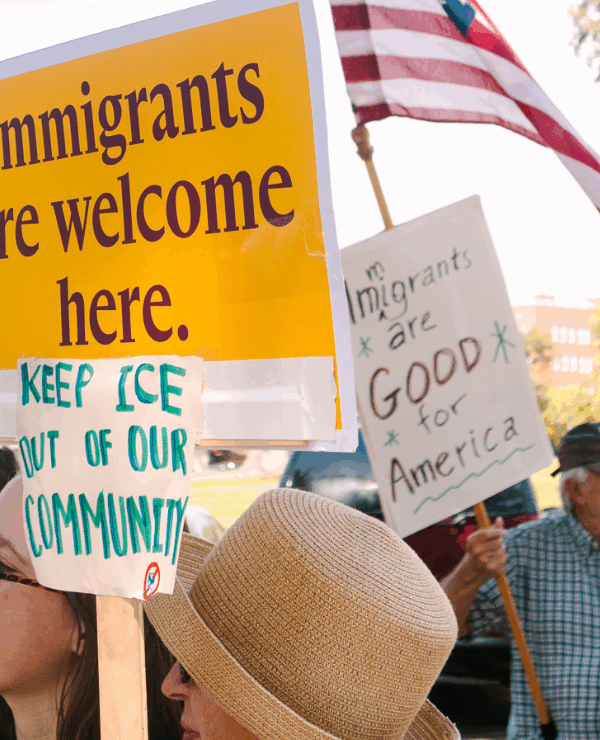 Rally attendees hold signs in support of immigrants at a demonstration outside the governor's mansion.