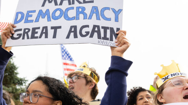 Omahans gather for a protest against federal overreach. A protester in the foreground holds a sign reading "Make Democracy Great again."