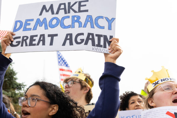 Omahans gather for a protest against federal overreach. A protester in the foreground holds a sign reading "Make Democracy Great again."