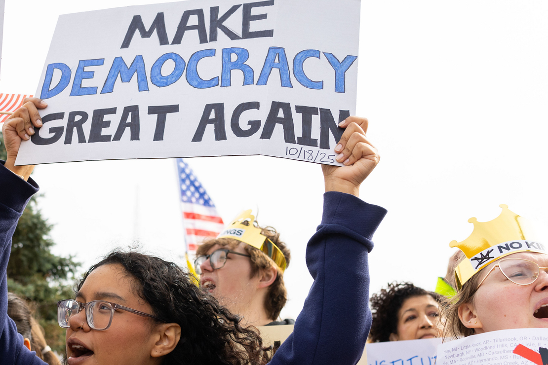 Omahans gather for a protest against federal overreach. A protester in the foreground holds a sign reading "Make Democracy Great again."